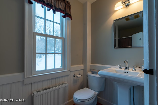 bathroom with toilet, radiator heating unit, and wainscoting