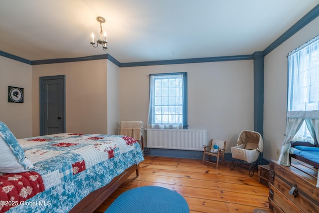 bedroom featuring multiple windows, radiator, hardwood / wood-style floors, and crown molding