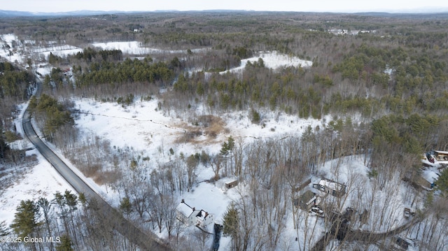 snowy aerial view with a mountain view and a wooded view