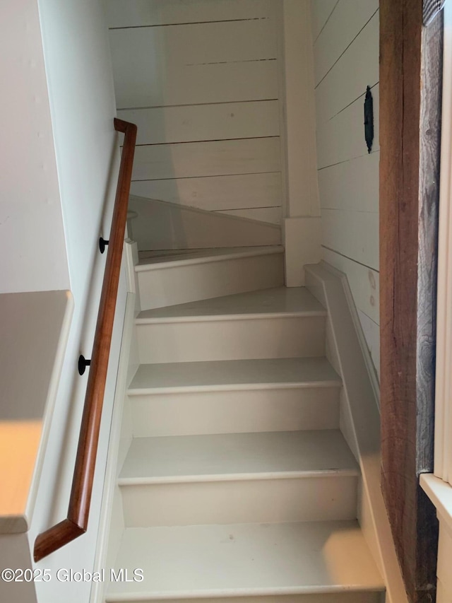 staircase featuring wood walls