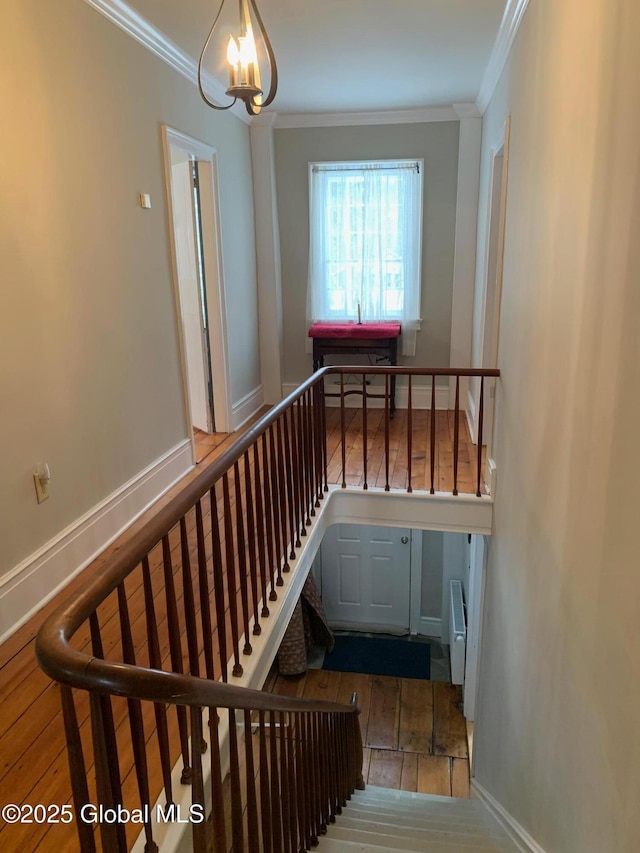 staircase with crown molding, baseboards, and wood finished floors