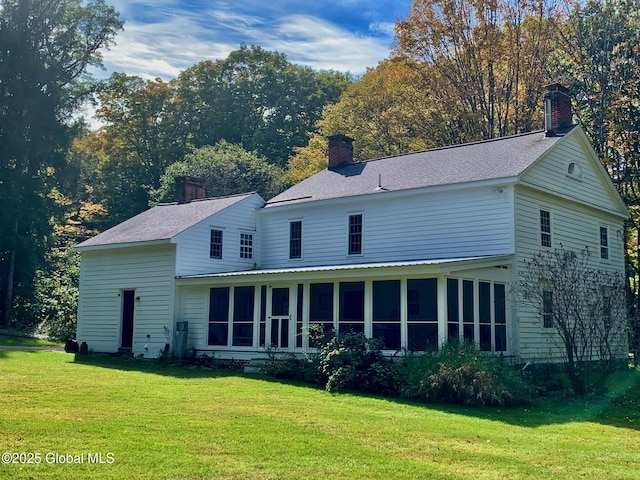 back of house with a chimney, a yard, and a sunroom