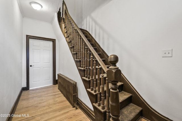 staircase featuring crown molding, baseboards, and wood finished floors