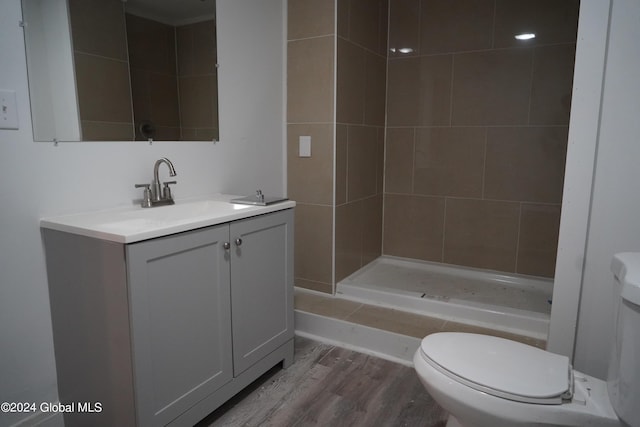 bathroom featuring wood finished floors, a stall shower, vanity, and toilet