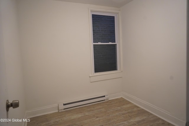 empty room with baseboards, baseboard heating, and wood finished floors