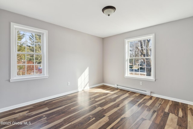 empty room with baseboard heating, wood finished floors, and baseboards