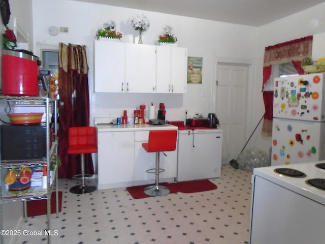 kitchen featuring light floors, white appliances, light countertops, and white cabinets