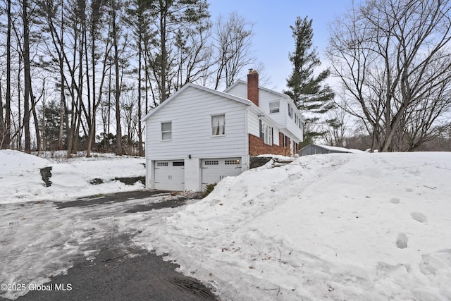 exterior space with a garage, brick siding, and a chimney