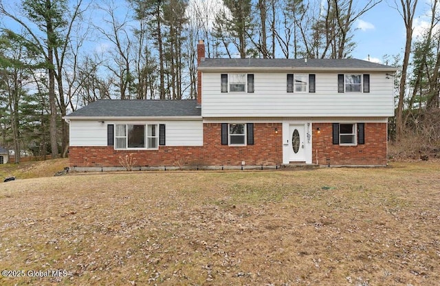 colonial house with a front lawn, a chimney, and brick siding