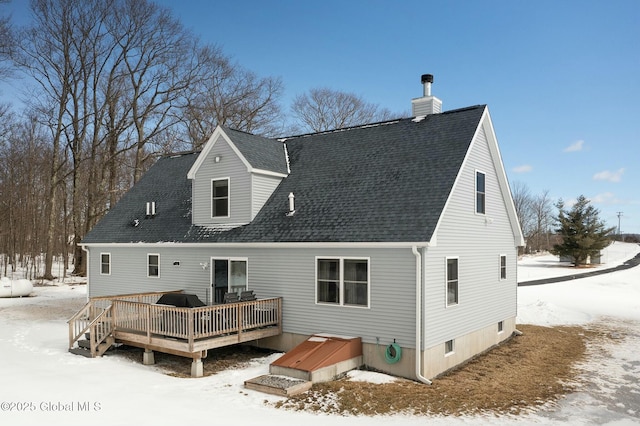 snow covered house featuring a shingled roof and a deck