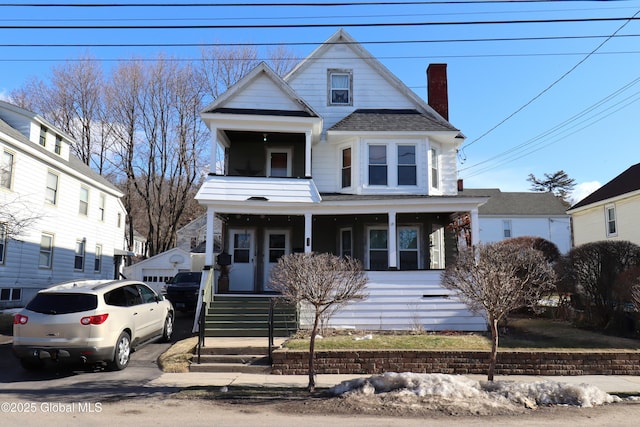 view of front of home featuring a shingled roof, a porch, a garage, and a chimney