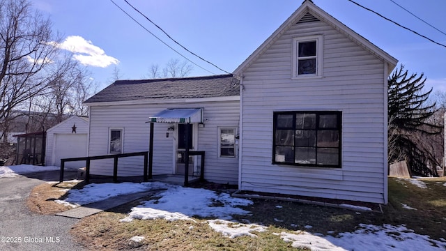 view of front of home featuring an outbuilding, driveway, roof with shingles, and a detached garage