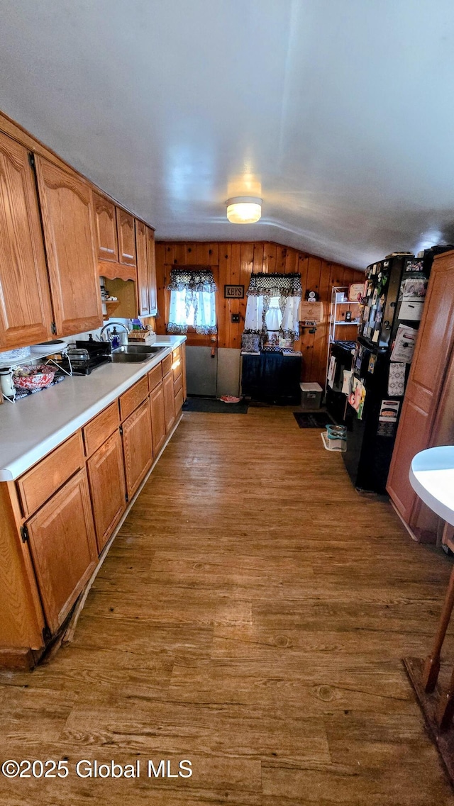 kitchen featuring a sink, vaulted ceiling, dark wood-style flooring, and light countertops