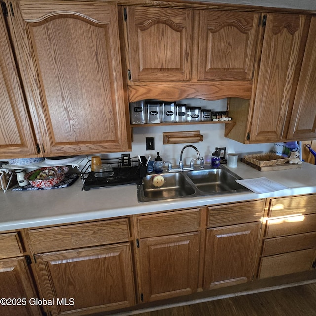 kitchen featuring light countertops, brown cabinetry, and a sink