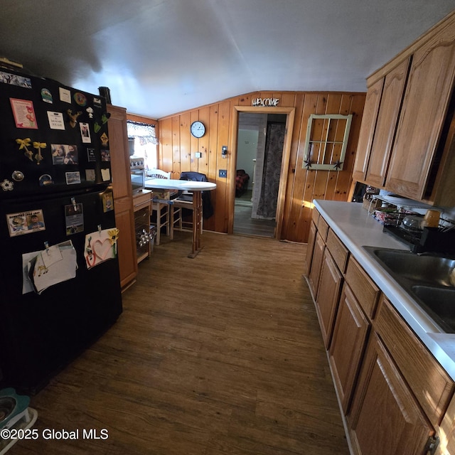 kitchen with dark wood finished floors, freestanding refrigerator, light countertops, vaulted ceiling, and a sink