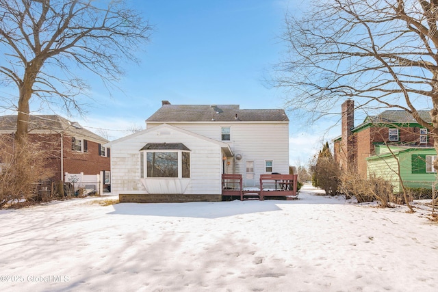 snow covered rear of property with fence, a chimney, and a wooden deck