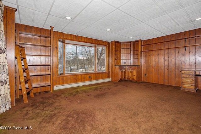 carpeted spare room featuring a baseboard heating unit, wood walls, and recessed lighting