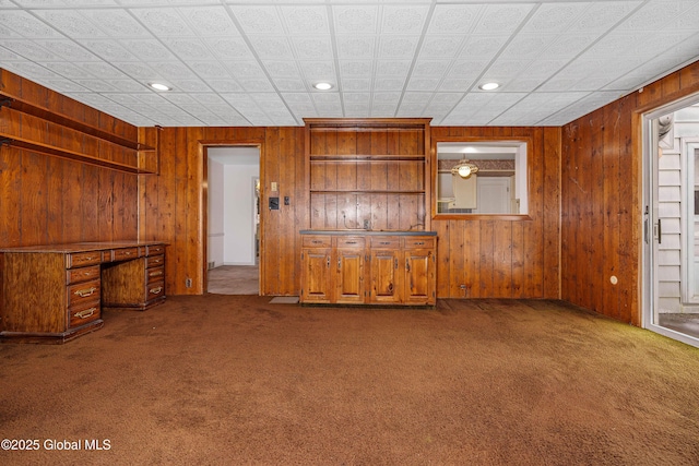 carpeted empty room with recessed lighting and wooden walls