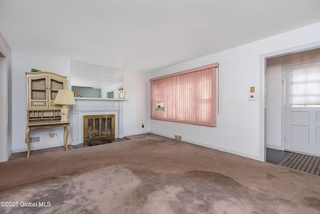 unfurnished living room with carpet flooring, a fireplace with flush hearth, visible vents, and baseboards