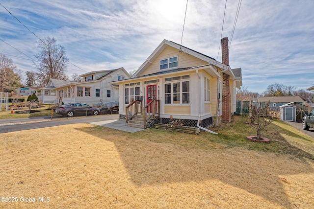 view of front of house featuring an outbuilding, a front yard, a chimney, and entry steps