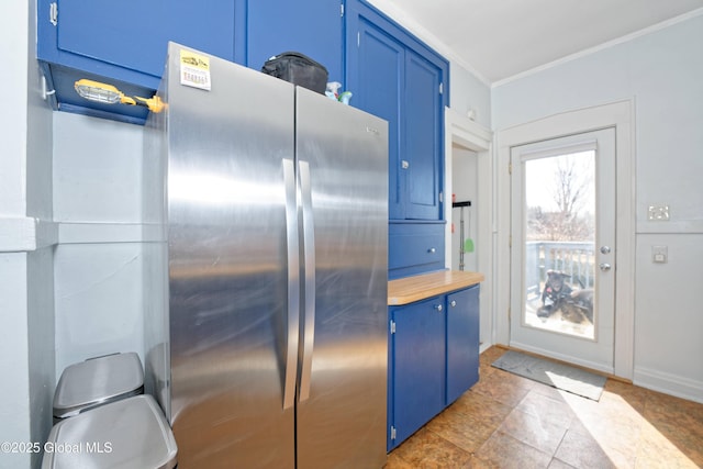 kitchen featuring blue cabinets, light countertops, crown molding, and freestanding refrigerator