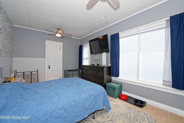 bedroom with baseboards, ornamental molding, carpet flooring, wainscoting, and a ceiling fan