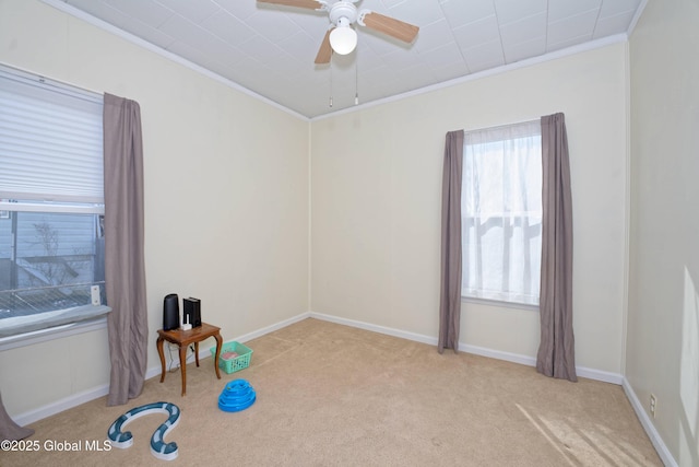 interior space with baseboards, a ceiling fan, and ornamental molding