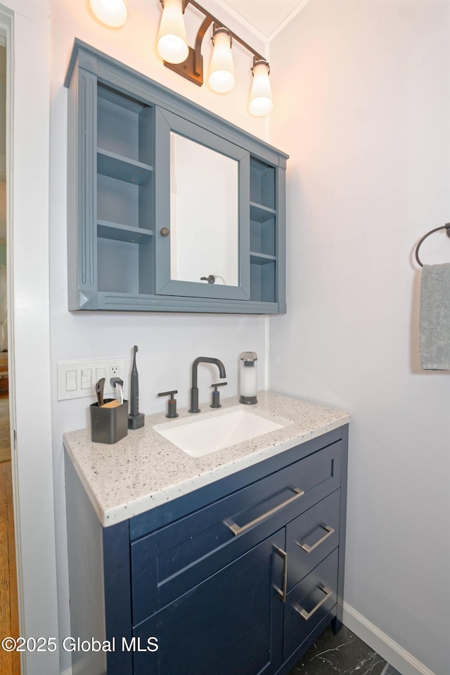 bathroom with marble finish floor, vanity, and baseboards