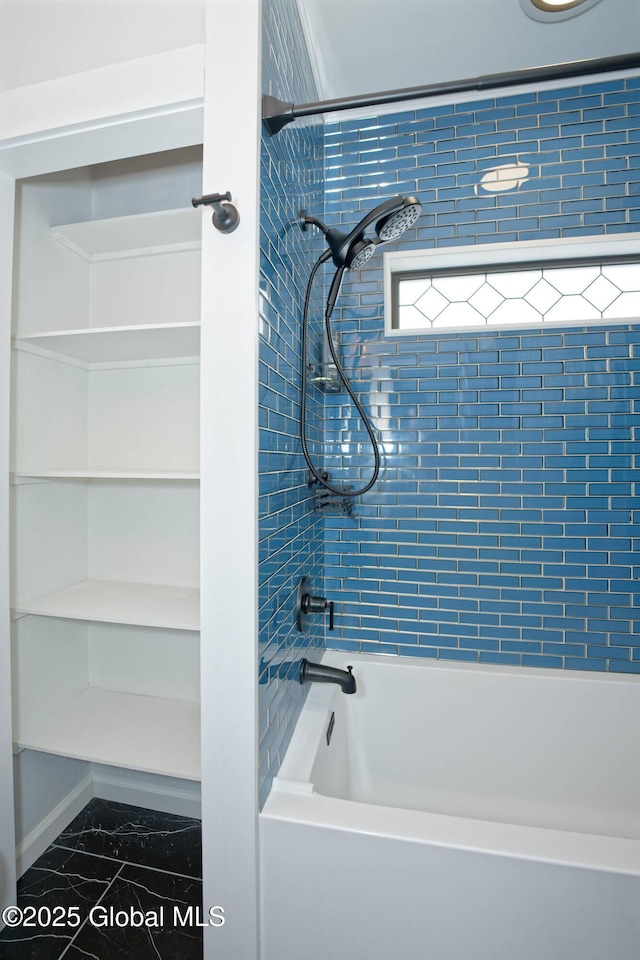 full bathroom with marble finish floor and washtub / shower combination