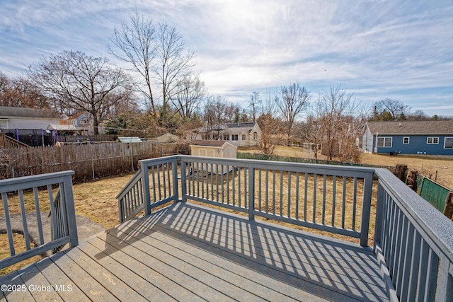 wooden deck featuring an outbuilding, a storage unit, a fenced backyard, and a residential view