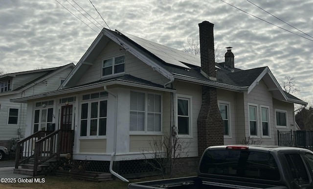 view of side of home with solar panels, entry steps, and a chimney