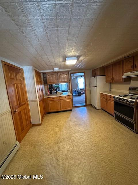 kitchen featuring range with gas cooktop, under cabinet range hood, light countertops, freestanding refrigerator, and a baseboard radiator