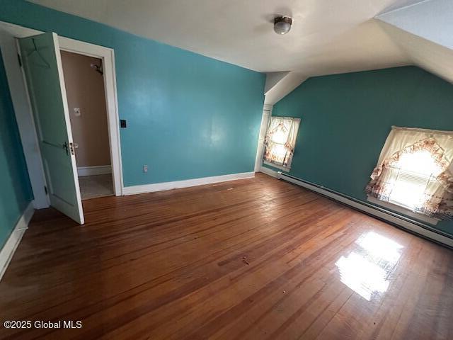 bonus room featuring baseboards, baseboard heating, wood finished floors, and vaulted ceiling