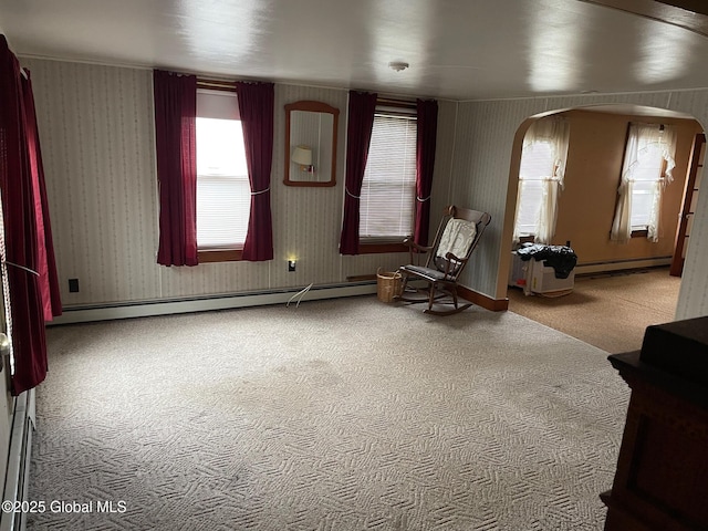 sitting room featuring a baseboard heating unit, arched walkways, carpet floors, and wallpapered walls