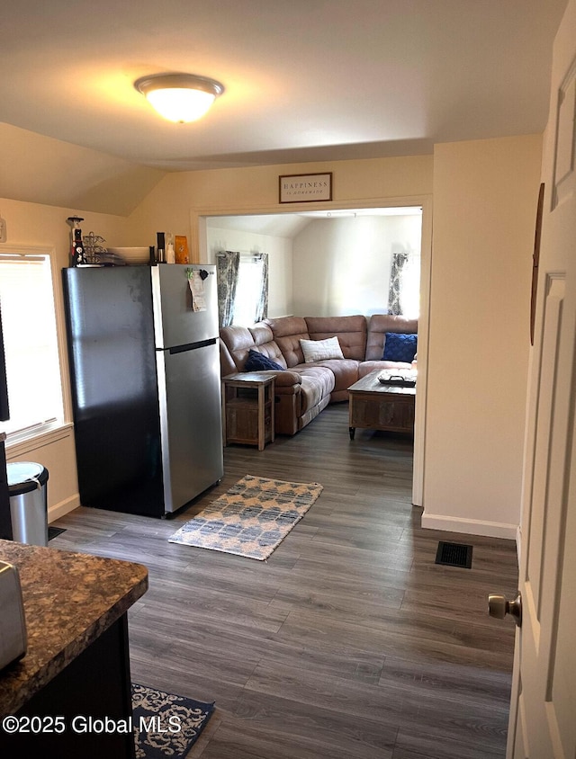 kitchen featuring dark countertops, dark wood-type flooring, plenty of natural light, and freestanding refrigerator