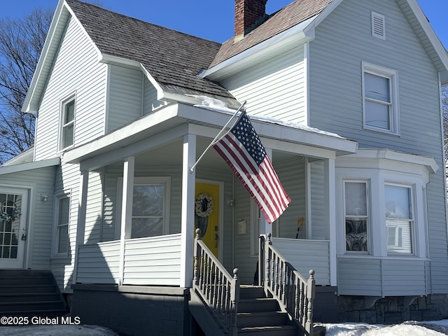 view of front of house featuring a chimney and a porch