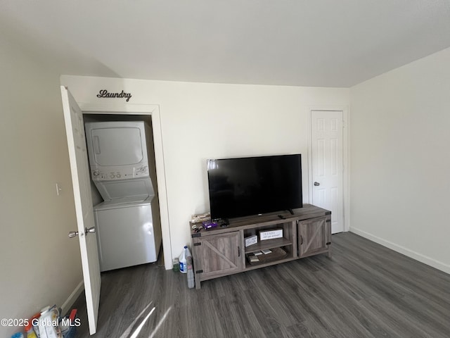 living area with dark wood-style flooring, stacked washer and clothes dryer, and baseboards