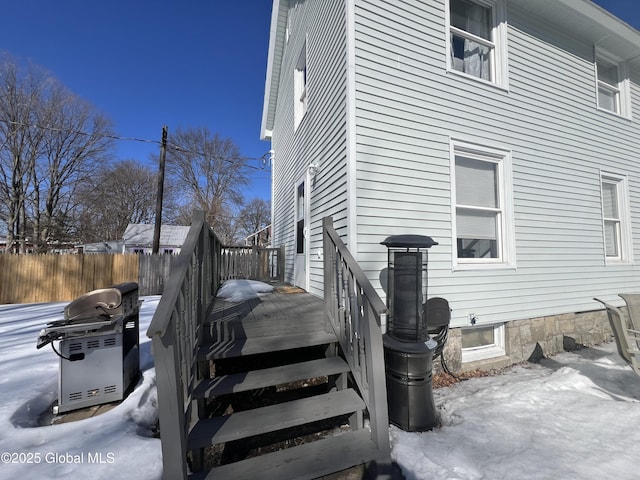 snow covered property featuring fence and a wooden deck