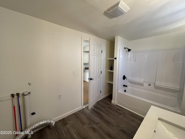 bathroom with washtub / shower combination, visible vents, baseboards, and wood finished floors