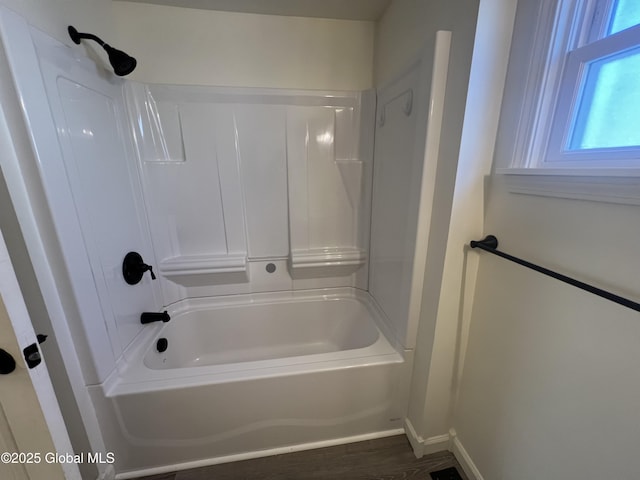 bathroom with shower / bathing tub combination, wood finished floors, and baseboards