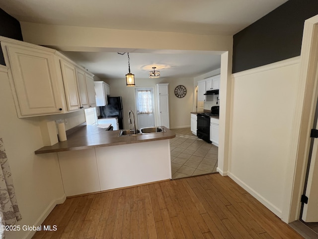 kitchen featuring light wood-style flooring, under cabinet range hood, a peninsula, a sink, and black appliances