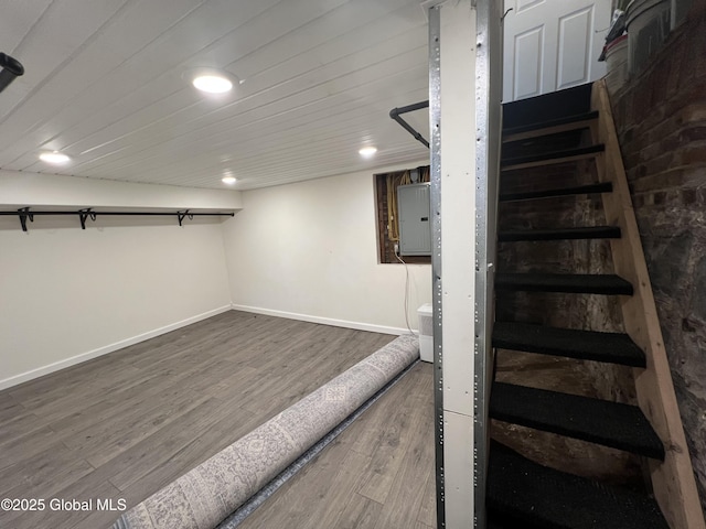 finished basement featuring recessed lighting, stairway, wood finished floors, electric panel, and baseboards