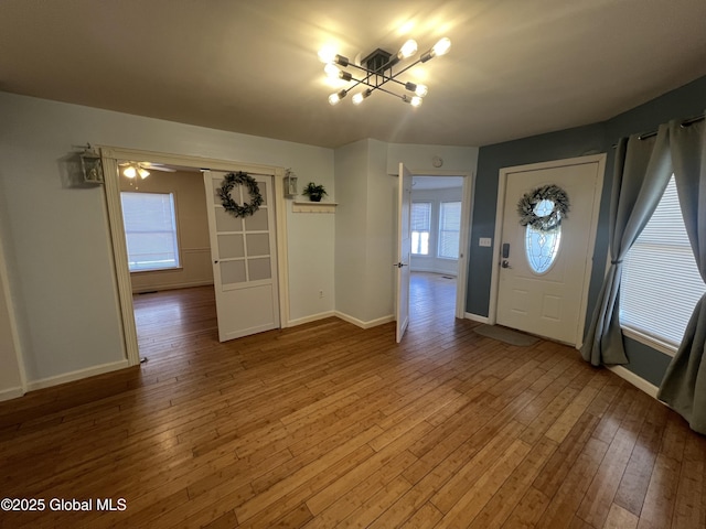 foyer featuring an inviting chandelier, wood-type flooring, and baseboards