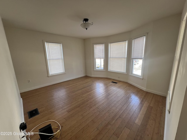 spare room featuring visible vents, baseboards, and wood finished floors