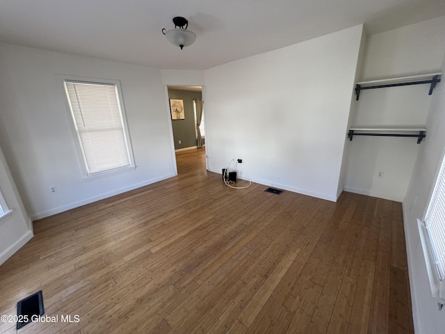 unfurnished bedroom with hardwood / wood-style flooring, visible vents, and baseboards