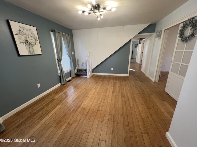 spare room featuring baseboards, an inviting chandelier, and hardwood / wood-style flooring