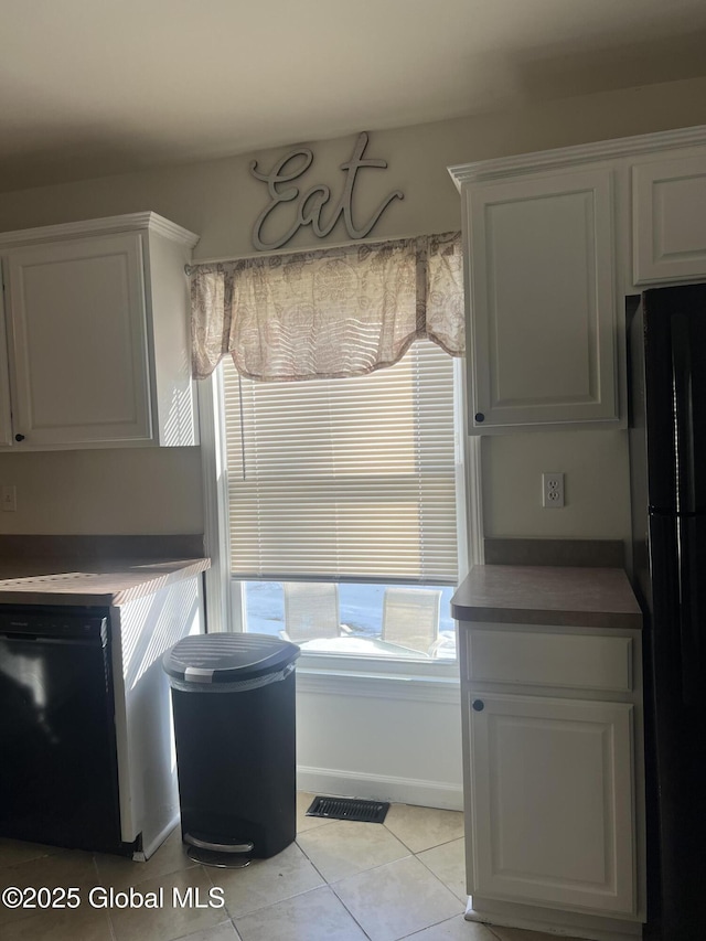 kitchen with black appliances, light tile patterned floors, visible vents, and white cabinets