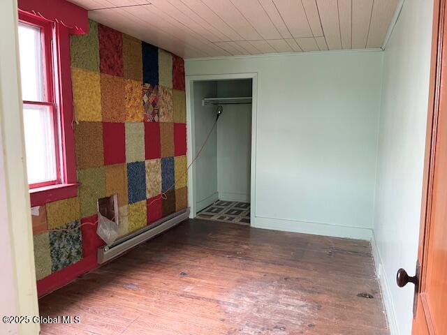 empty room featuring ornamental molding, baseboards, and wood finished floors