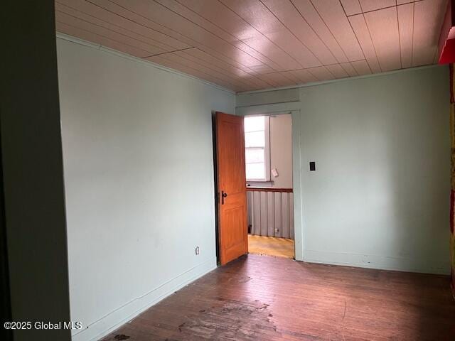 spare room with baseboards and wood finished floors