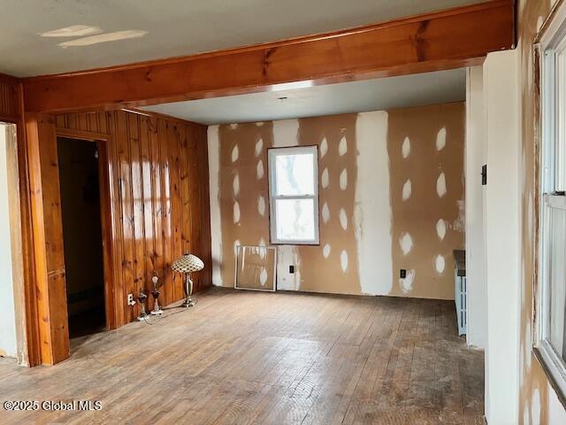 spare room with wood-type flooring, beamed ceiling, and wood walls